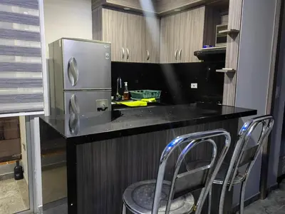 a kitchen with a counter with a refrigerator and chairs at Quiet space near Nórdica with parking in Bello
