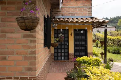 a brick house with a black door and baskets of flowers at Villa El Colibri in El Peñol
