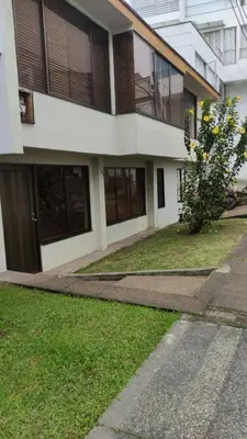a building with a grass yard in front of it at Hotel Casa Guayacanes in Manizales