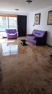 a living room with purple couches and a table at Hotel Casa Guayacanes in Manizales