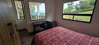 a bedroom with a bed and a desk and two windows at El Encanto - El Peñol in Chiquinquirá