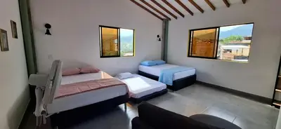 a small room with two beds and two windows at Apartamento en Santa Fe de Antioquia con jacuzzi in Santa Fe de Antioquia