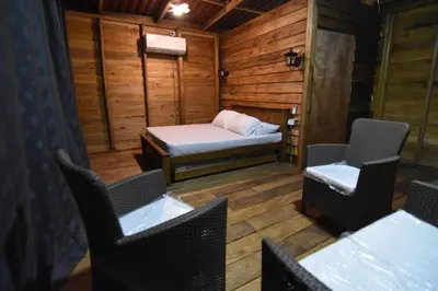 a room with a bed and chairs in a cabin at Cabañas naturales cerca a la hacienda Nápoles in Doradal
