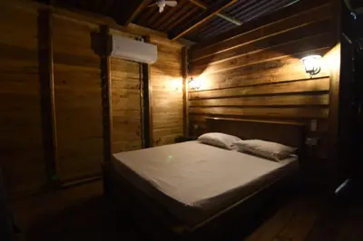 a bed in a wooden room with two pillows at Cabañas naturales cerca a la hacienda Nápoles in Doradal