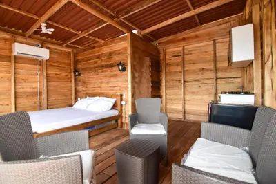 a room with a bed and chairs in a cabin at Cabañas naturales cerca a la hacienda Nápoles in Doradal