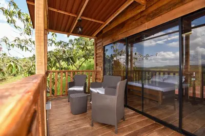 a room with a balcony with a bed and chairs at Cabañas naturales cerca a la hacienda Nápoles in Doradal