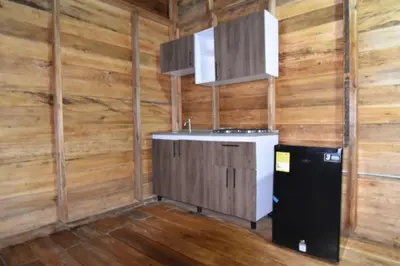 a kitchen with wooden walls and a sink and a refrigerator at Cabañas naturales cerca a la hacienda Nápoles in Doradal