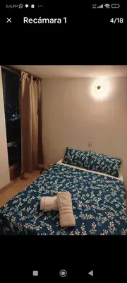 a bed with a blue comforter with two towels on it at Apartamento en excelente ubicación en el Poblado para renta con estadía mínima de 1 mes in Medellín