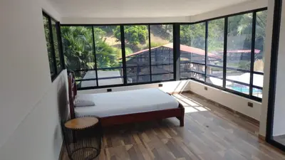 a room with a bed and a balcony with windows at Finca Hotel Rancho Cattleya in Chinchiná