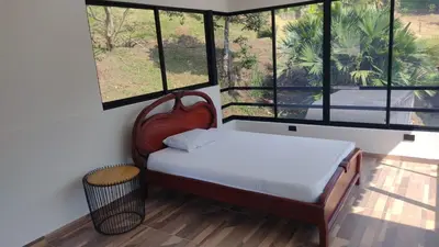 a bedroom with a bed with a chair and windows at Finca Hotel Rancho Cattleya in Chinchiná