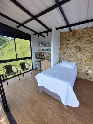 a bedroom with a bed and a stone wall at Cabaña Refugio Amani in Norcasia