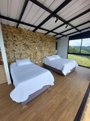 two beds in a room with a stone wall at Cabaña Refugio Amani in Norcasia