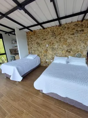 two beds in a room with a stone wall at Cabaña Refugio Amani in Norcasia