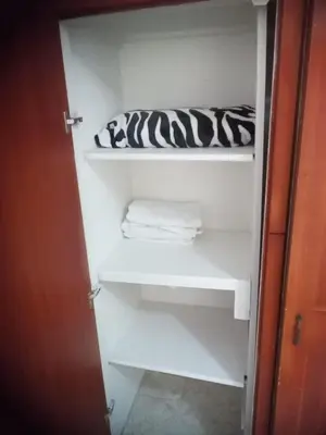 a closet with white shelves and towels in it at Habitación central con cama doble #1 in Medellín