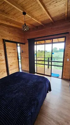 a bedroom with a large bed in a room with windows at Cabaña Martina in Marinilla