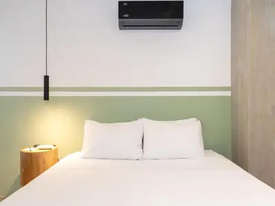 a bedroom with a white bed with a tv above it at NOK Spectacular 3 BR w Balcony in Laureles Medellin in Medellín