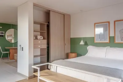 a bedroom with a white bed and a green wall at NOK Stylish Studio w Balcony in Laureles Medellin in Medellín
