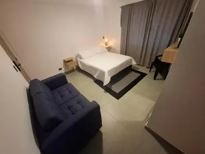 a bedroom with a bed and a couch and a chair at Hotel La Casona Estadio in Medellín