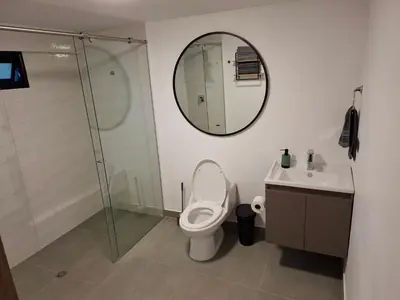 a bathroom with a toilet and a sink and a mirror at Hotel La Casona Estadio in Medellín