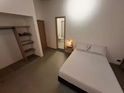 a bedroom with a white bed and a mirror at Hotel La Casona Estadio in Medellín
