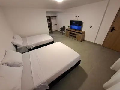 a hotel room with two beds and a television at Hotel La Casona Estadio in Medellín