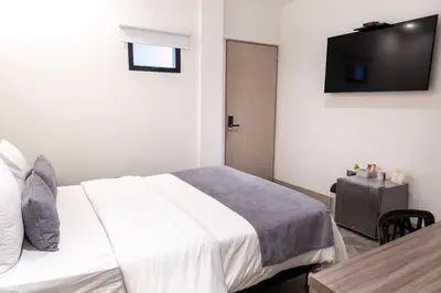 a bedroom with a bed and a tv on the wall at Hotel Laureles Loft in Medellín