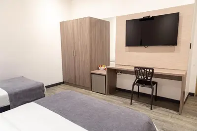 a hotel room with a television and a desk with a chair at Hotel Laureles Loft in Medellín
