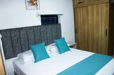 a bedroom with a white bed with blue pillows at Pura Vida in Quibdó
