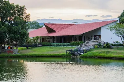 a building with a red roof next to a body of water at Hotel Brisas La Gaviota Mariquit-Tolima in Mariquita