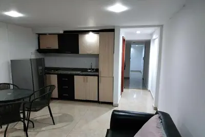 a living room with a couch and a table and a kitchen at Rento apartamento por días in Manizales