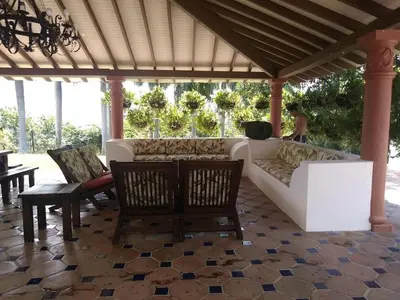a living room with a couch and chairs on a patio at Villa Kelly Farm in San Jerónimo
