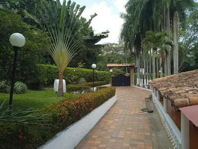 a walkway in a garden with palm trees and flowers at Villa Kelly Farm in San Jerónimo