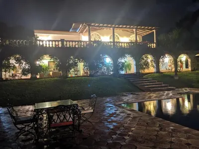 a building with a bridge over a pond at night at Villa Kelly Farm in San Jerónimo