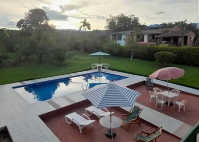 a pool with umbrellas and chairs and a table and chairs at Finca El Refugio Familiar in Manizales