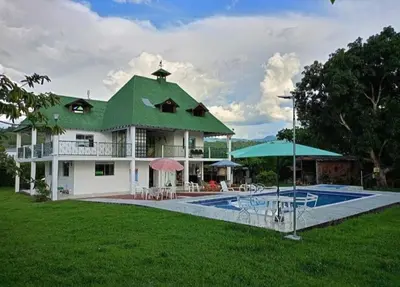 a house with a green roof and a swimming pool at Finca El Refugio Familiar in Manizales