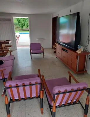 a living room with purple chairs and a flat screen tv at Finca El Refugio Familiar in Manizales