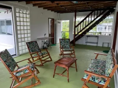 a porch with rocking chairs and a table and stairs at Finca El Refugio Familiar in Manizales