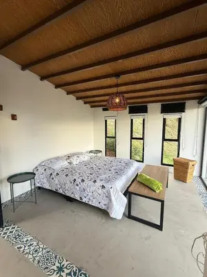a large bedroom with a bed and a table at Cabaña Hogar del Bosque in Palestina