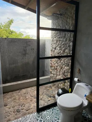 a bathroom with a toilet and a stone wall at Cabaña Hogar del Bosque in Palestina