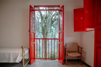 a red door leading to a bedroom with a tree at Hacienda Santa Bárbara Coffee Farm in La Linda