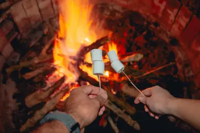 two people holding two marshmallows over a fire at Hacienda Santa Bárbara Coffee Farm in La Linda