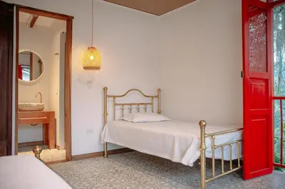 a bedroom with a bed and a red door at Hacienda Santa Bárbara Coffee Farm in La Linda