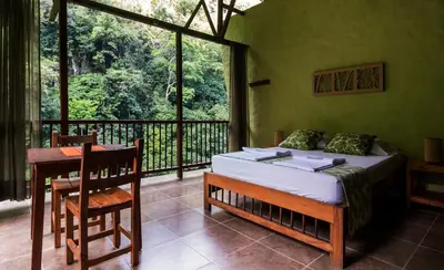 a bedroom with a bed and a table and a balcony at Rio Claro Reserva Natural in San Francisco