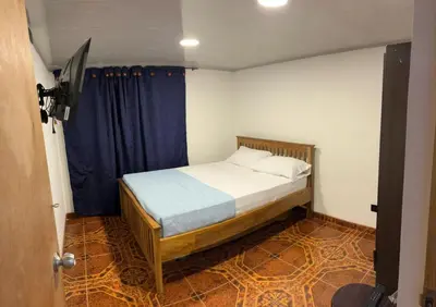 a small bedroom with a bed with a blue curtain at Plaza de Toros & Centro Ubicación Ideal in Manizales