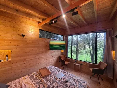a bedroom with a bed in a room with wooden walls at Boheme Cabin in Medellín