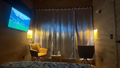 a bedroom with a television and a yellow chair at Boheme Cabin in Medellín