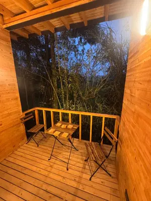 a wooden porch with a table and chairs on it at Boheme Cabin in Medellín