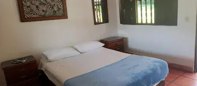 a small bedroom with a bed and two windows at Finca Hotel El Juncal in Venecia