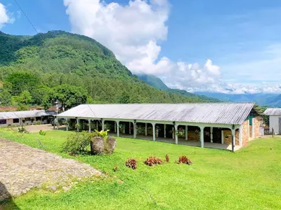 a building in a field with a mountain in the background at Finca Hotel El Juncal in Venecia