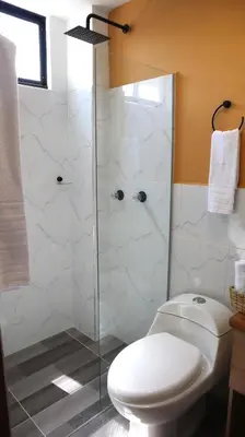 a bathroom with a toilet and a glass shower at GIO Green Hotel Girardota Medellin in Girardota